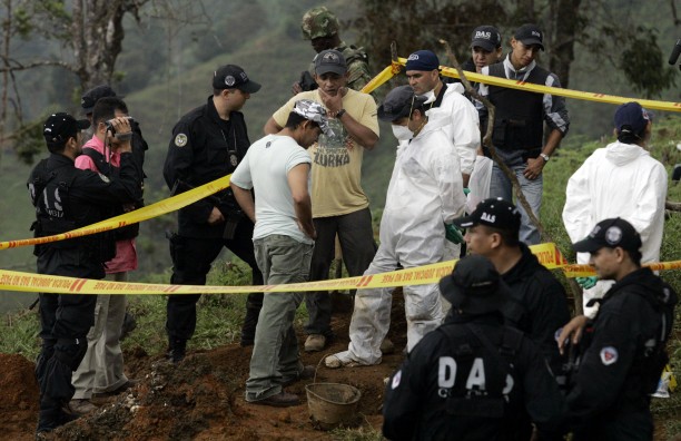 Colombian police look at the human remains found in a mass grave of at least 20 bodies in El Arenillo, northeast of Cali, Colombia in 2008. Elkin Casarrubia, a.k.a. "Don Mario," center with his hand to his face, former leader of the United Self-Defense Forces of Colombia (AUC) who headed the Calima paramilitary block, led authorities to the site.