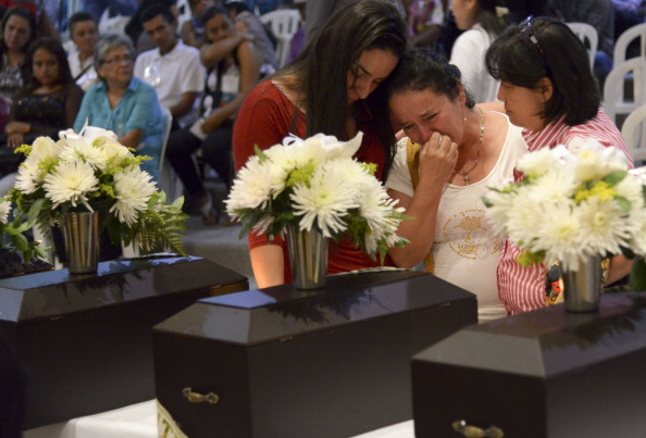 A woman is conforted as she cries next to a funerary urn with the remains of her relative disappeared during the Colombian civil war, in a ceremony in Medellin, Colombia on March 21, 2014. Relatives of 18 victims received the remains of their loved ones, which were recently found in common graves due to information given by demobilized combatants of both sides, the leftist guerrillas and the right-wing paramilitary groups, in the framework of the country's peace process. 