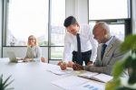 two-smiling-businessmen-discussing-paperwork-7YPYP9Q-1.jpg